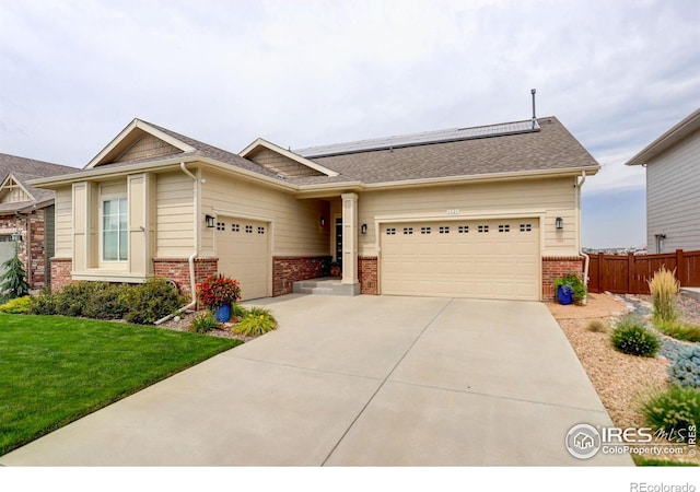 craftsman-style home featuring a garage, brick siding, fence, and roof mounted solar panels