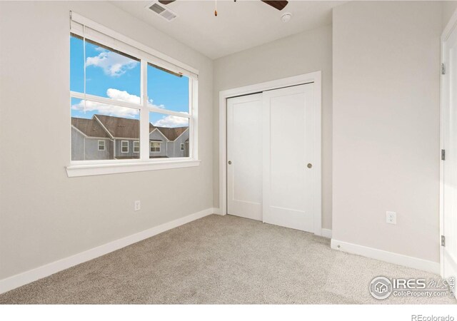 unfurnished bedroom with ceiling fan, light carpet, and a closet