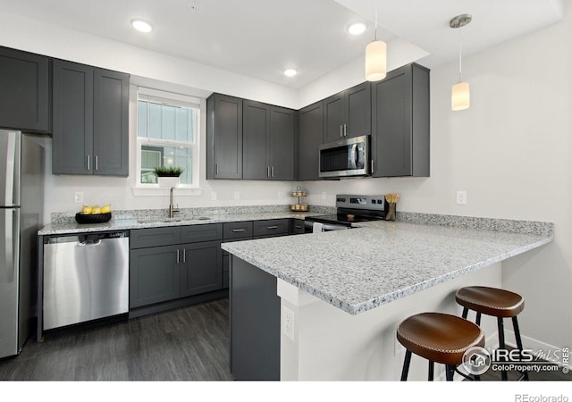 kitchen with kitchen peninsula, appliances with stainless steel finishes, hanging light fixtures, and sink