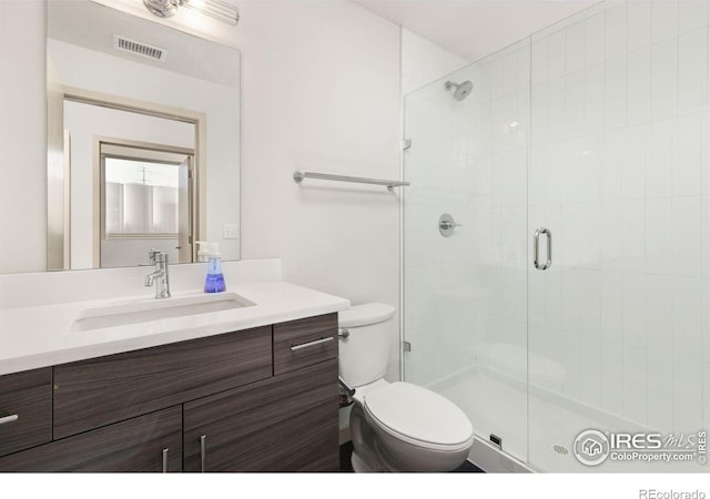 bathroom featuring vanity, walk in shower, and toilet