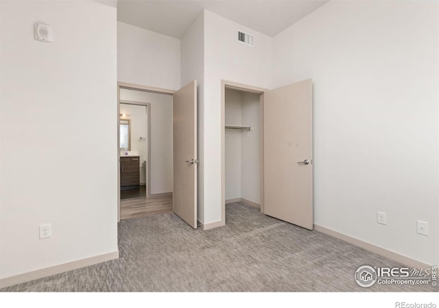 unfurnished bedroom with light colored carpet and a closet