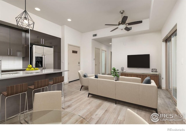 living room featuring ceiling fan, sink, and light hardwood / wood-style floors