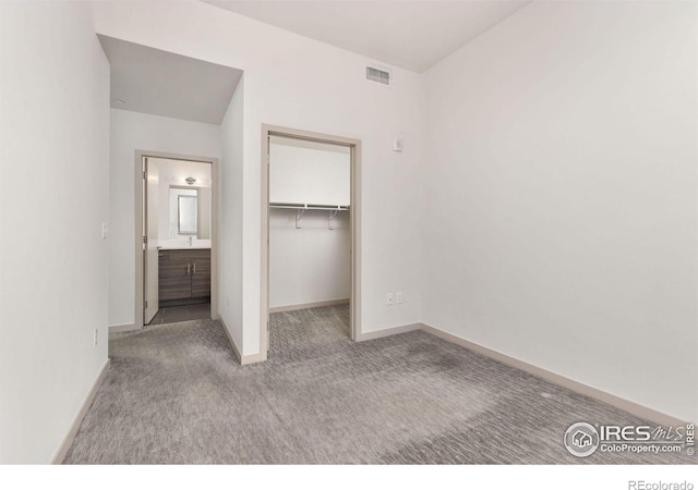 unfurnished bedroom featuring a walk in closet, light colored carpet, and a closet