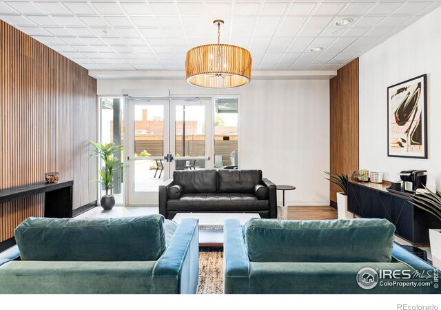 living room featuring wooden walls, wood-type flooring, and french doors