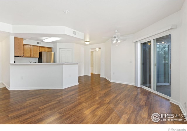 unfurnished living room with dark hardwood / wood-style flooring and ceiling fan