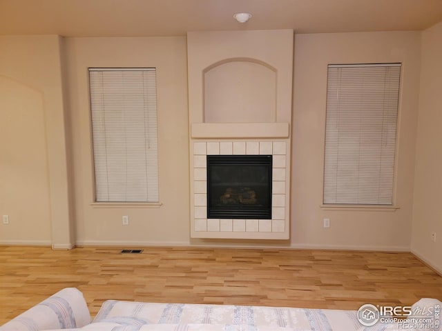 unfurnished living room featuring light wood-type flooring and a tile fireplace