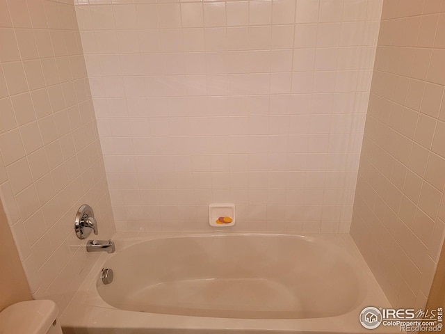 bathroom featuring toilet and tiled shower / bath combo