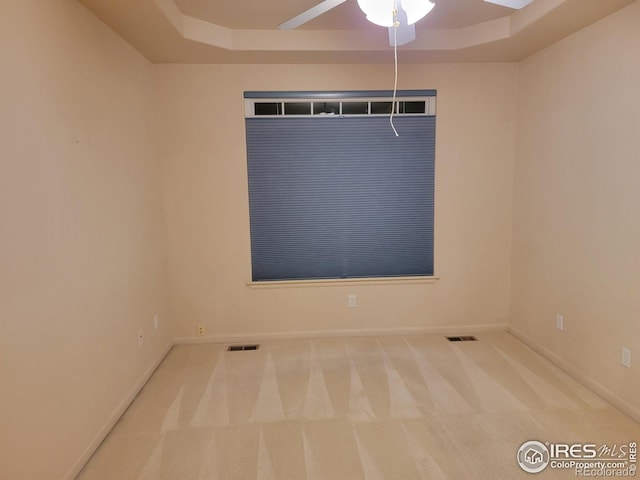 carpeted empty room featuring ceiling fan and a tray ceiling