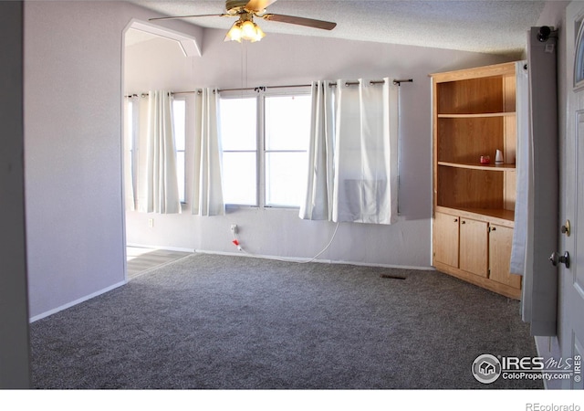 carpeted spare room with lofted ceiling, a textured ceiling, and ceiling fan