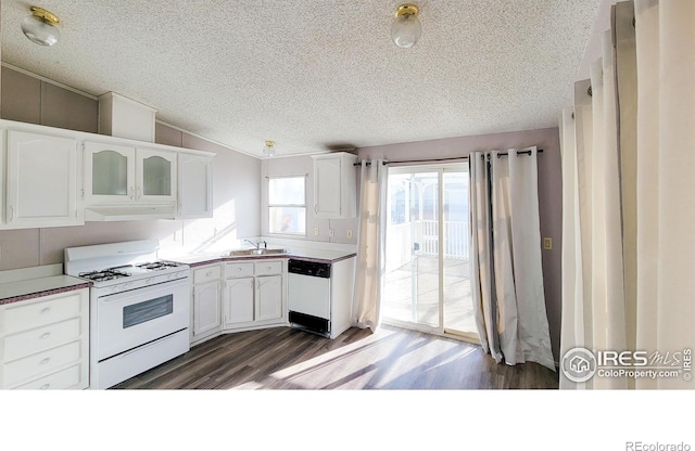 kitchen featuring white appliances, dark wood-type flooring, white cabinets, lofted ceiling, and sink