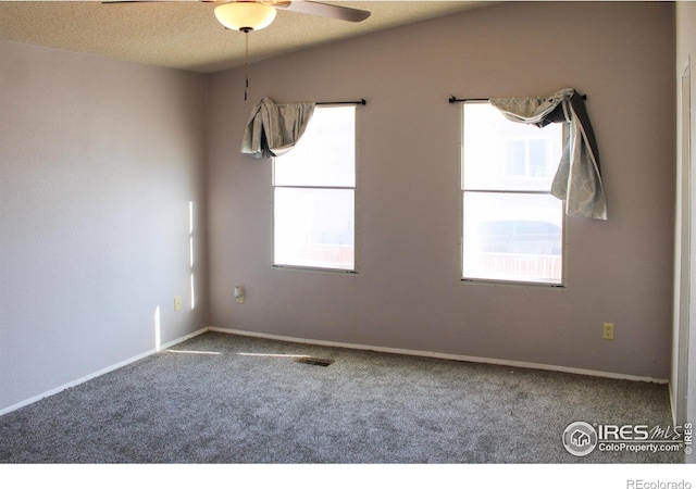 carpeted empty room with ceiling fan, a textured ceiling, and plenty of natural light