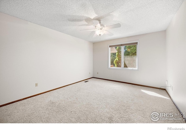 carpeted spare room featuring ceiling fan, a textured ceiling, visible vents, and baseboards