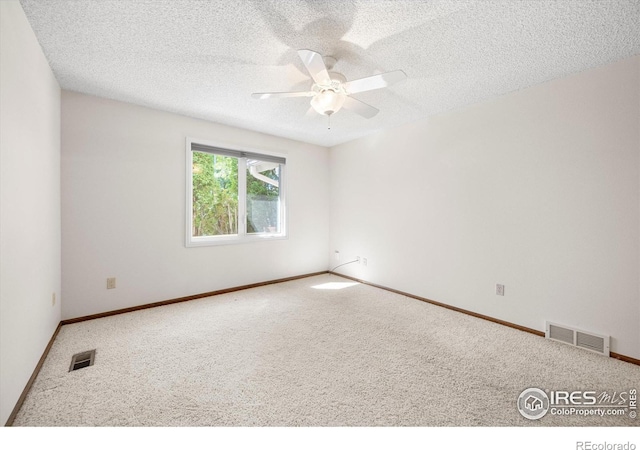 spare room featuring a textured ceiling, carpet flooring, visible vents, and a ceiling fan