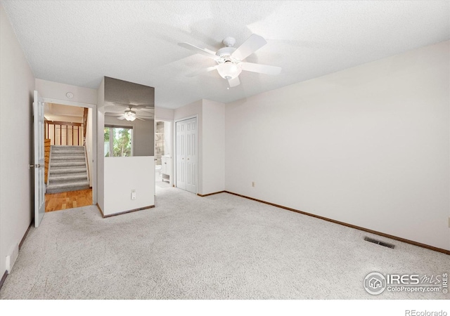 unfurnished bedroom with visible vents, light carpet, a textured ceiling, and baseboards