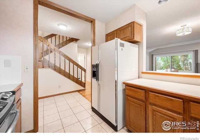 kitchen with brown cabinets, stainless steel stove, light countertops, a textured ceiling, and white fridge with ice dispenser