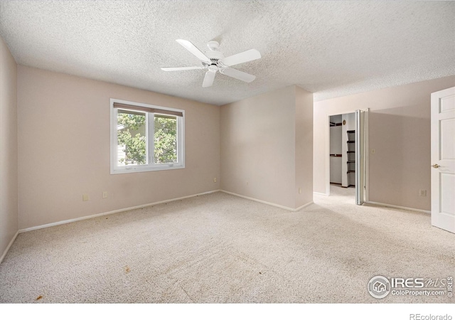 spare room featuring a ceiling fan, light colored carpet, a textured ceiling, and baseboards