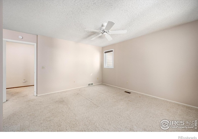 unfurnished room featuring light colored carpet, ceiling fan, visible vents, and a textured ceiling