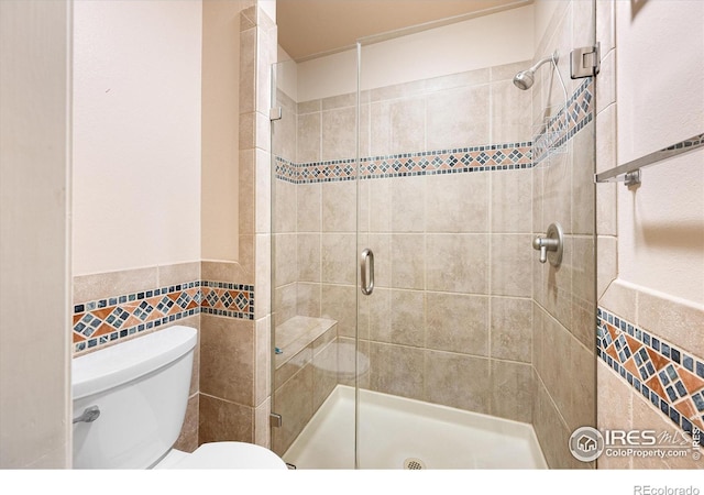 bathroom with toilet, a wainscoted wall, a shower stall, and tile walls