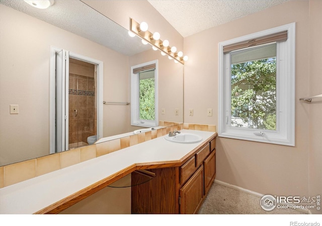 bathroom featuring baseboards, tiled shower, toilet, a textured ceiling, and vanity