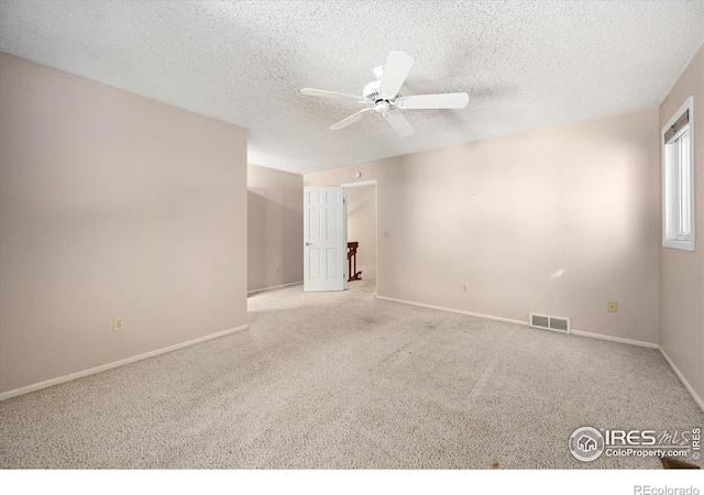 empty room with ceiling fan, a textured ceiling, visible vents, and light colored carpet