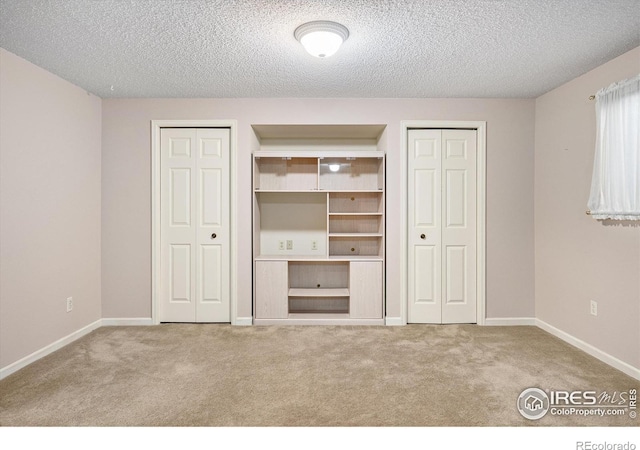 unfurnished bedroom with light carpet, baseboards, and two closets