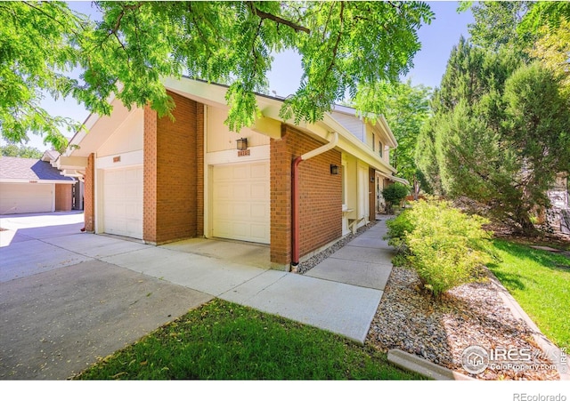 view of front of property featuring a garage, concrete driveway, and brick siding