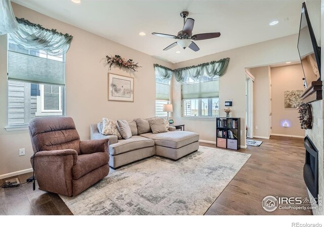 living room featuring hardwood / wood-style floors, ceiling fan, and a fireplace