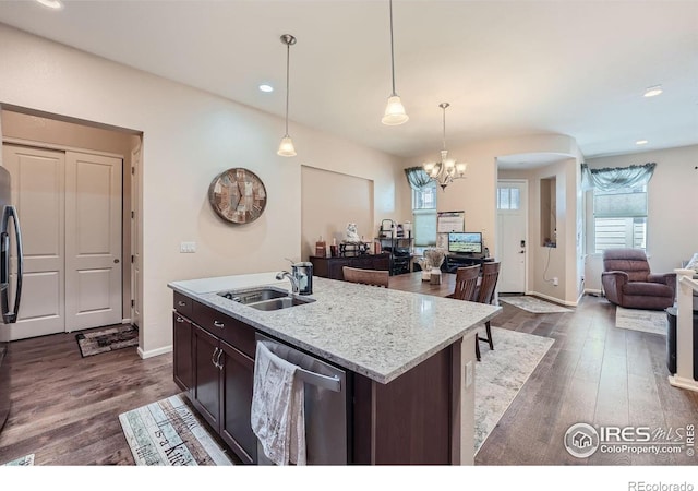 kitchen featuring stainless steel dishwasher, sink, a center island with sink, pendant lighting, and dark wood-type flooring