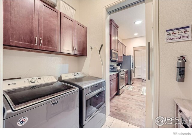 washroom with light hardwood / wood-style floors, independent washer and dryer, and cabinets