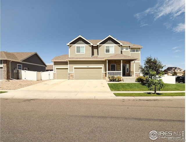 craftsman inspired home with a front lawn, fence, covered porch, stone siding, and driveway