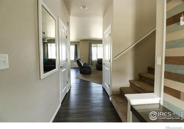 hallway with dark wood finished floors, stairway, baseboards, and a textured wall