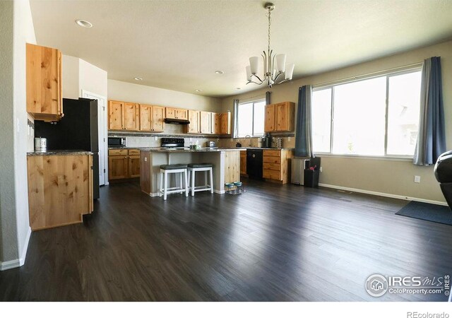 kitchen with a center island, a notable chandelier, dark hardwood / wood-style flooring, a breakfast bar area, and hanging light fixtures