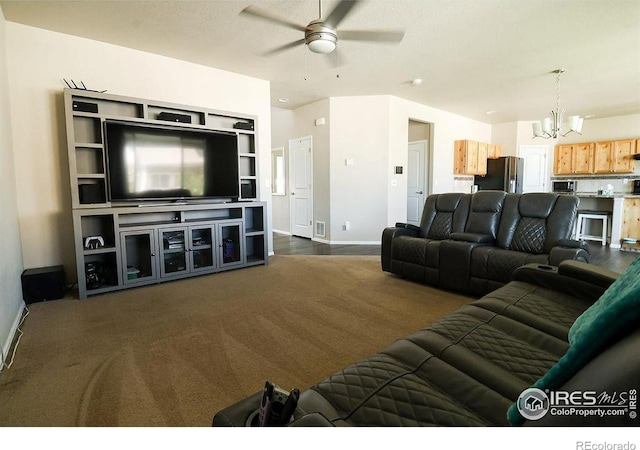 living room featuring dark colored carpet and ceiling fan with notable chandelier