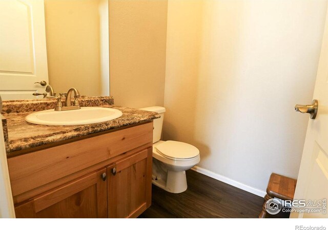 bathroom with toilet, hardwood / wood-style flooring, and vanity