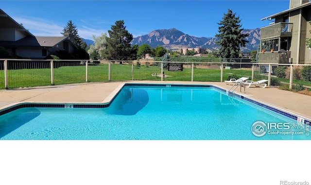 view of swimming pool featuring a mountain view and a lawn