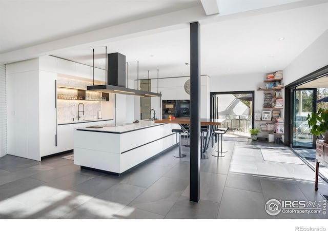 kitchen featuring island range hood, white cabinetry, sink, and black electric cooktop