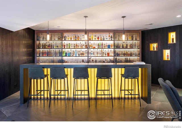 bar featuring decorative light fixtures and wood walls