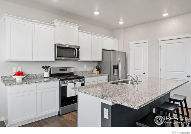 kitchen featuring appliances with stainless steel finishes, white cabinetry, sink, a center island with sink, and dark hardwood / wood-style flooring