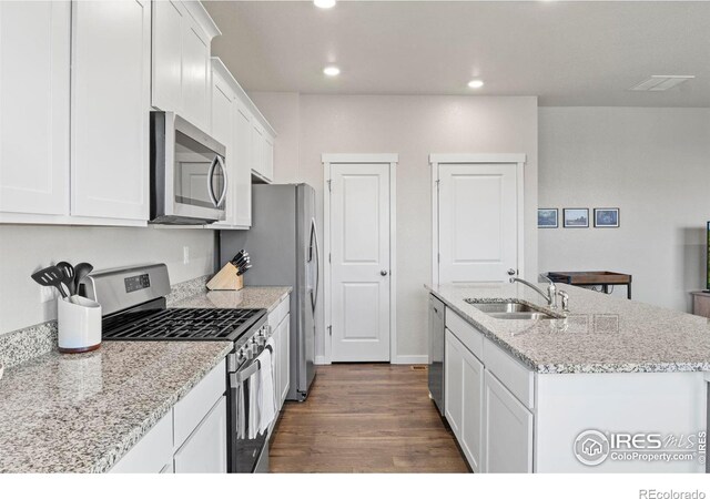 kitchen with appliances with stainless steel finishes, white cabinetry, sink, a kitchen island with sink, and dark wood-type flooring