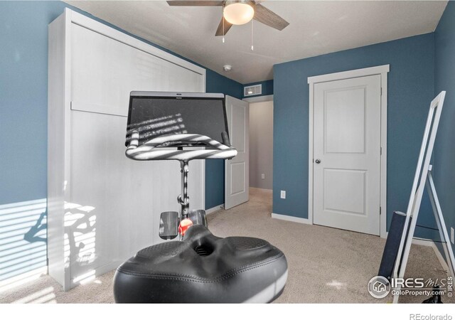 workout area featuring ceiling fan and light colored carpet