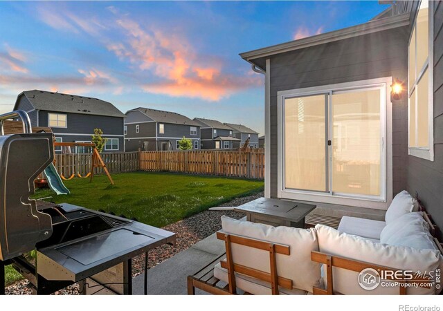 patio terrace at dusk with an outdoor living space, a playground, and a lawn