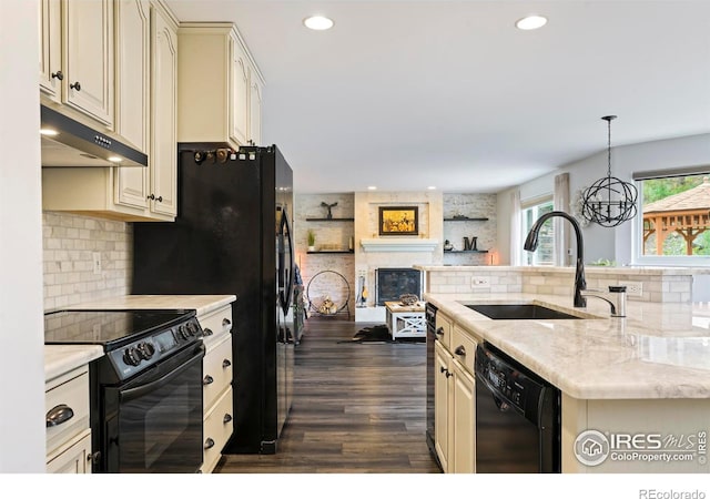 kitchen featuring sink, hanging light fixtures, dark hardwood / wood-style floors, cream cabinetry, and black appliances