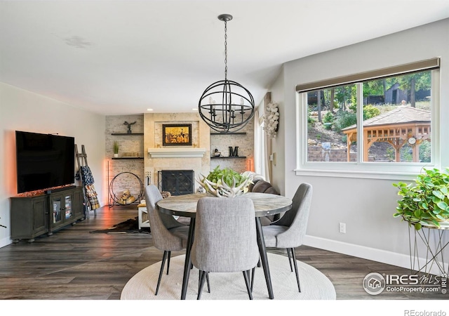 dining room featuring a fireplace, an inviting chandelier, and dark wood-type flooring