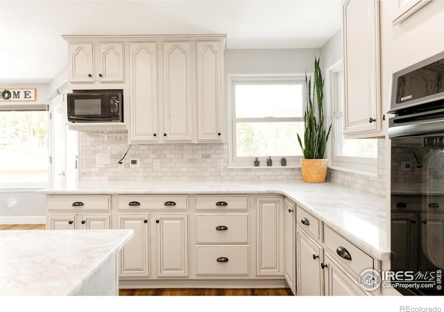 kitchen with decorative backsplash, light stone counters, and light hardwood / wood-style flooring