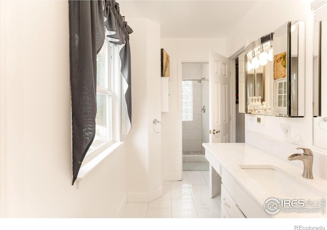 bathroom with a tile shower and vanity