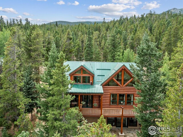 back of house with a wooded view, metal roof, and a deck with mountain view