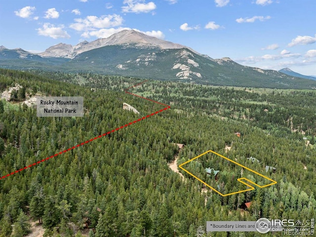 aerial view of property's location featuring a forest, a mountain backdrop, and property boundaries highlighted