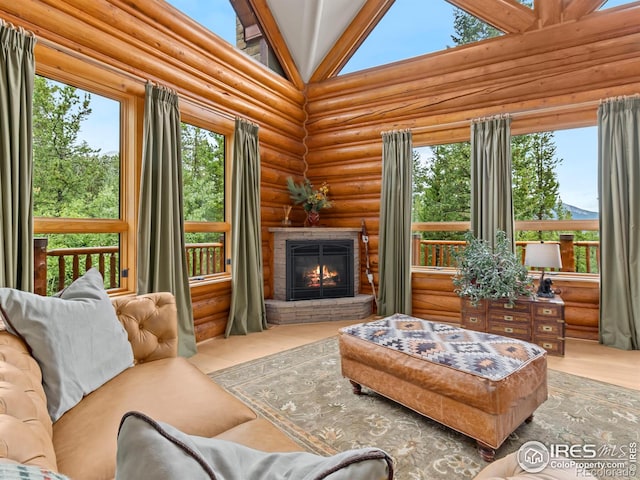 living room with log walls, a glass covered fireplace, high vaulted ceiling, and wood finished floors