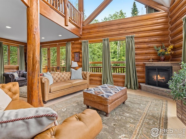 living area featuring log walls, a glass covered fireplace, wood finished floors, recessed lighting, and a high ceiling