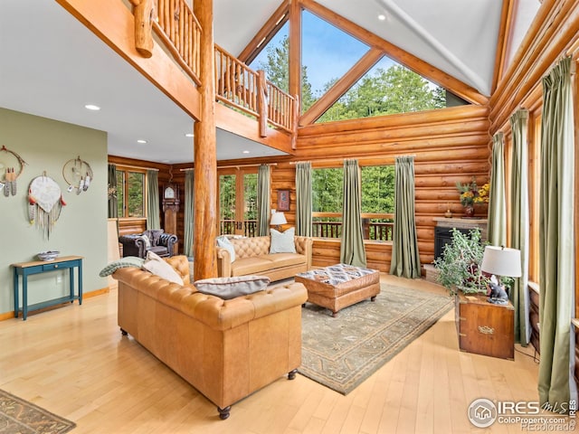 living room with rustic walls, healthy amount of natural light, hardwood / wood-style floors, baseboards, and high vaulted ceiling